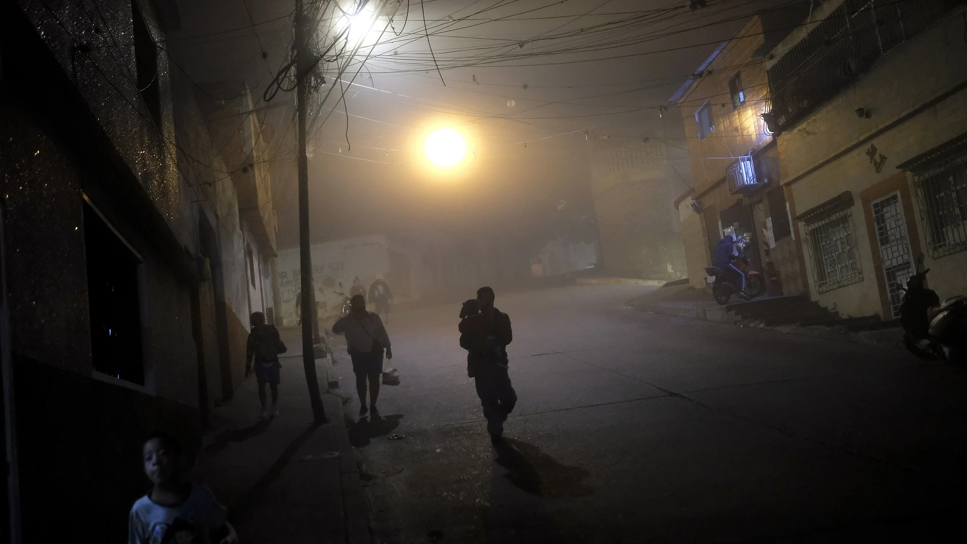Vecinos atraviesan casi a oscuras una barriada de Caracas