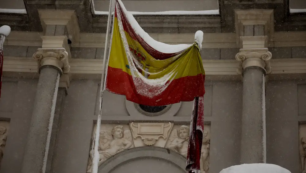 MADRID, 09/01/2021.- La bandera de España congelada sobre el Teatro Real en la Plaza de Oriente Madrid