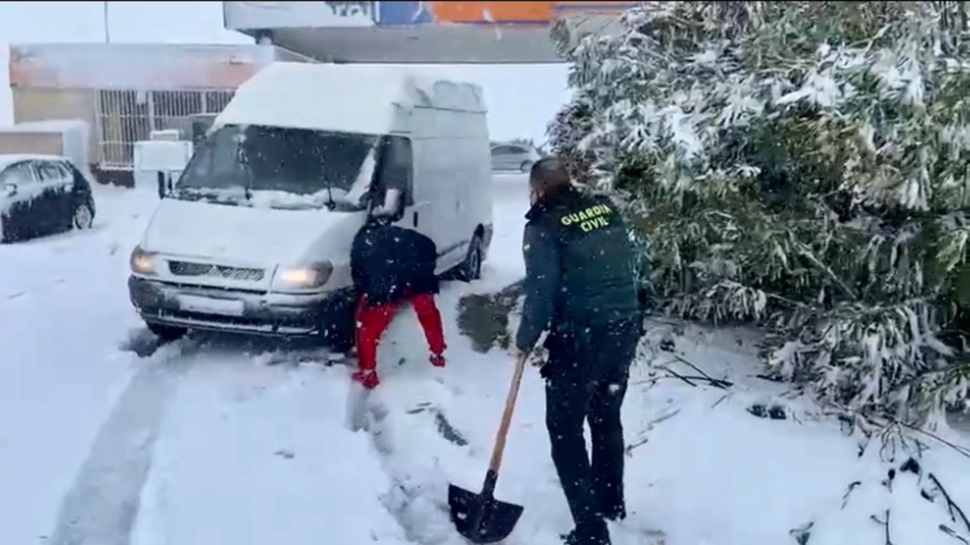 Un guardia civil, pala en mano, ayuda a una furgoneta atrapada en la nieve en Escalona (Toledo)