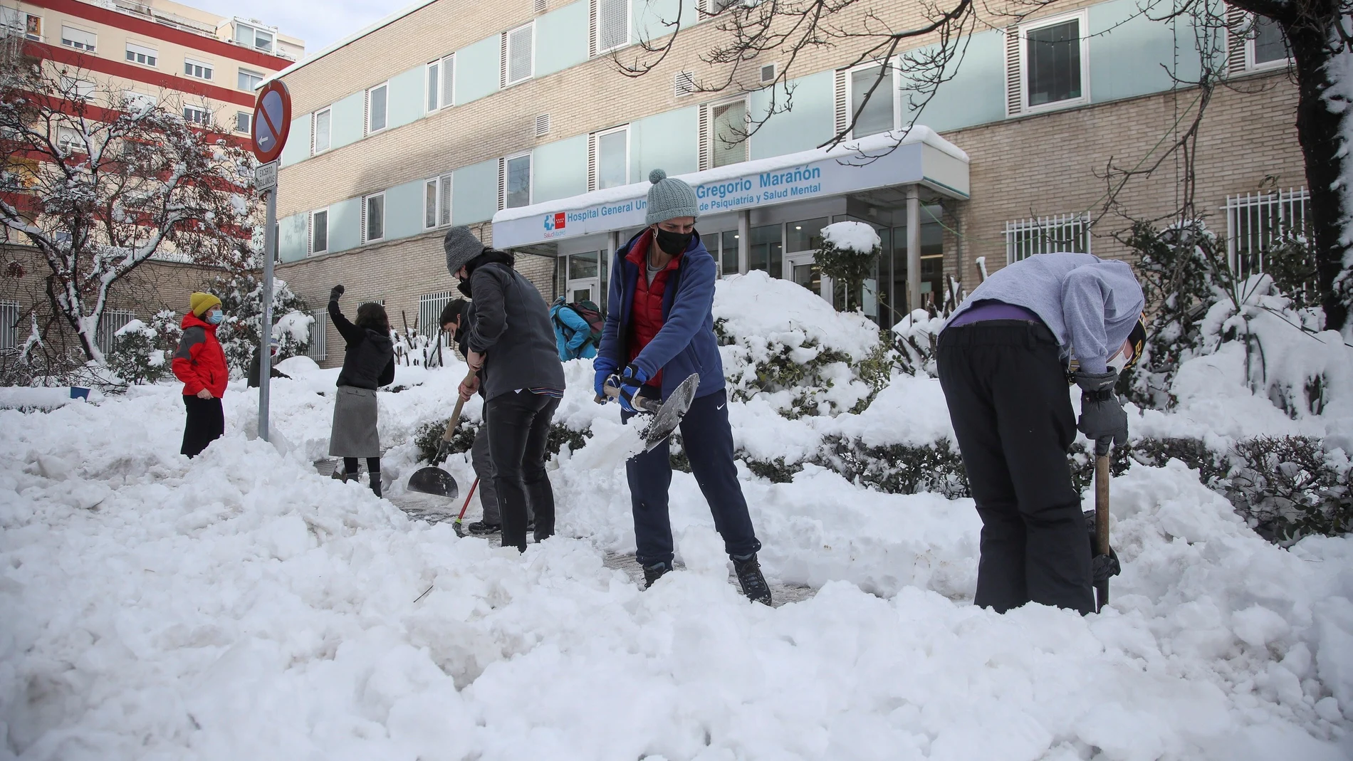 MADRID, 10/01/2021.- Varios voluntarios despejan con palas el acceso a una de las entradas del Hospital Gregorio Marañon de Madrid, cubierto de una gruesa capa de nieve tras el paso de la borrasca Filomena. EFE/David Fernández