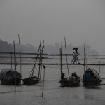 Indian girls walk on a temporary footbridge to board on a ferry as fishermen take rest in their boats in the river Brahmaputra in Gauhati, in the northeastern state of Assam, India, Monday, Jan. 11, 2021. Brahmaputra is one of Asia's largest rivers, which passes through China's Tibet region, India and Bangladesh before converging into the Bay of Bengal. (AP Photo/Anupam Nath)