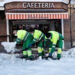 Trabajadores municipales limpian el acceso a una cafetería de Madrid.
