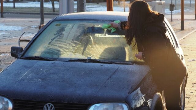 Imagen de archivo de una mujer quitando el hielo de su coche