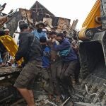 Un grupo de jóvenes rescata a un hombre que se había quedado bajo los escombros de un edificio gubernamental tras el terremoto en Mamuju,  Indonesia