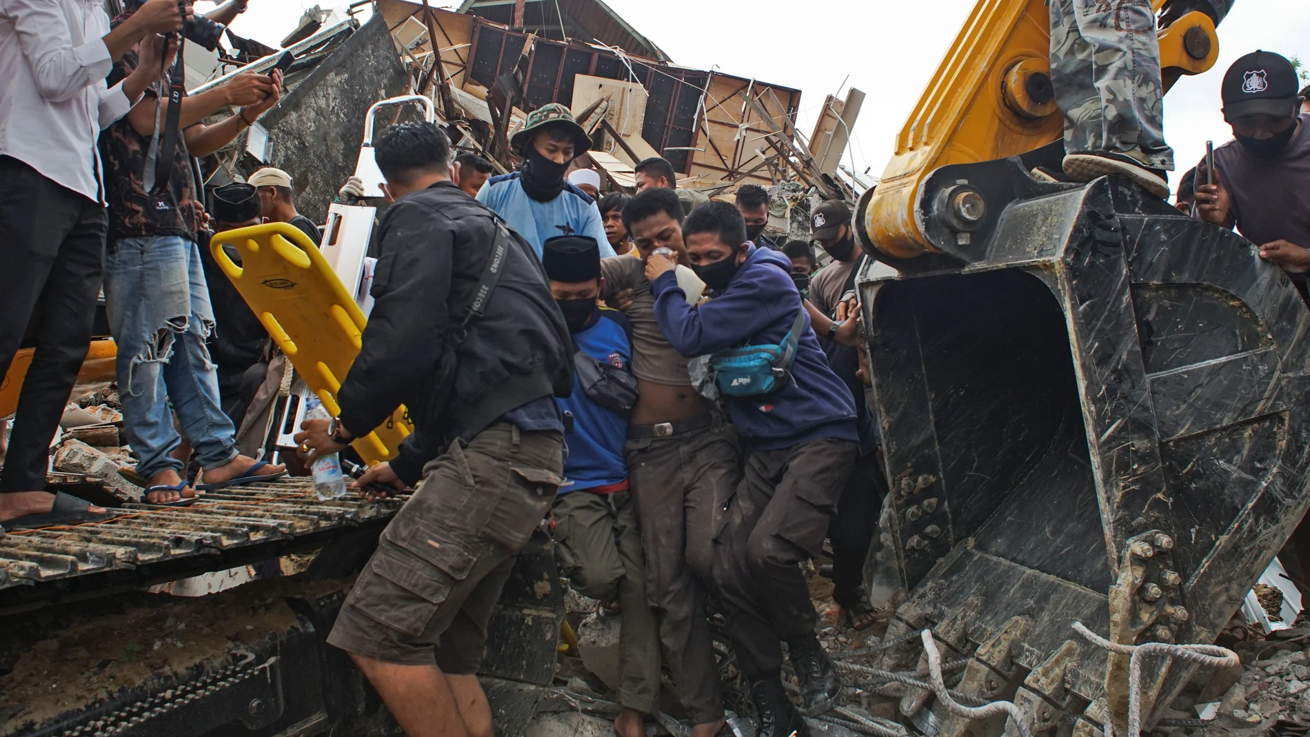 Un grupo de jóvenes rescata a un hombre que se había quedado bajo los escombros de un edificio gubernamental tras el terremoto en Mamuju, Indonesia