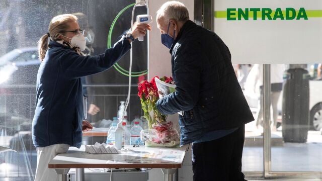 Una celadora del Hospital Reina Sofía de Murcia toma la temperatura a un hombre a la entrada al hospital