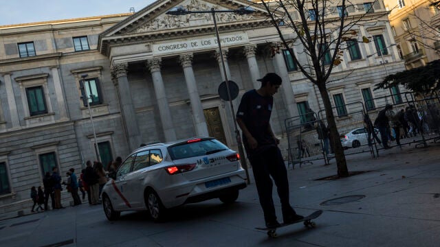 Transeúntes pasan frente a la Fachada del Congreso de los Diputados.