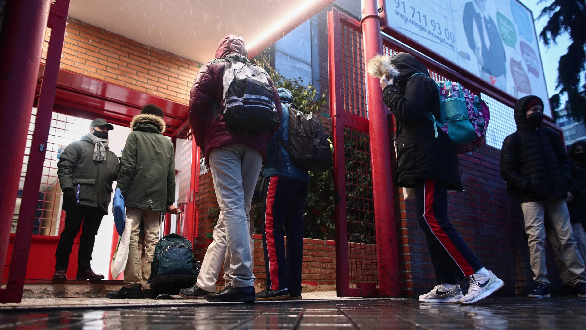 Varios alumnos esperan antes de entrar al colegio Arcángel Rafael el día de la reapertura de los centros educativos tras la gran nevada registrada por el paso de ‘Filomena’, en Aluche, Madrid