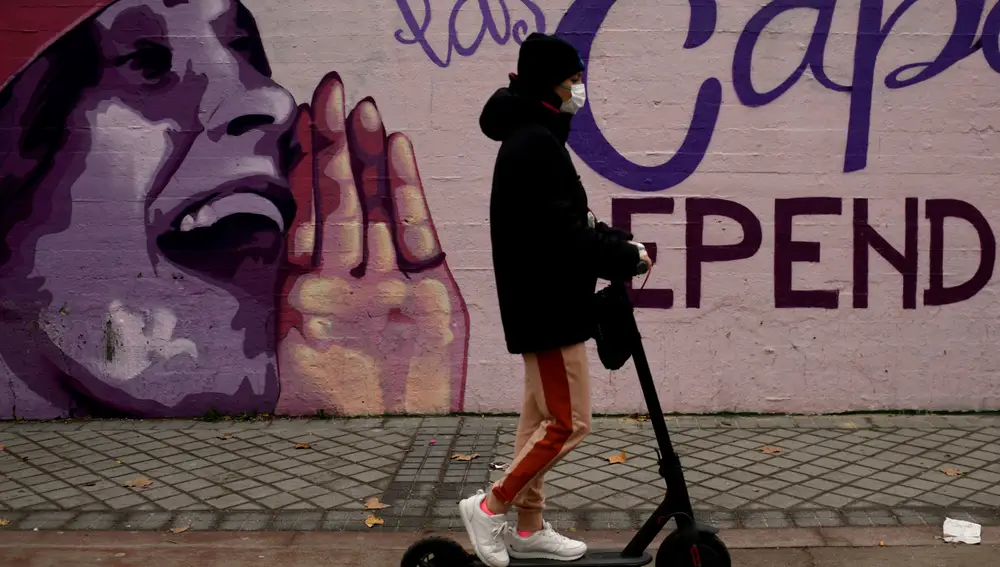 Una mujer pasa con un patín por el mural feminista en el polideportivo municipal de la Concepción en el distrito de Ciudad Lineal que será proximamente borrado tras una iniciativa de Vox en el Ayuntamiento de Madrid.