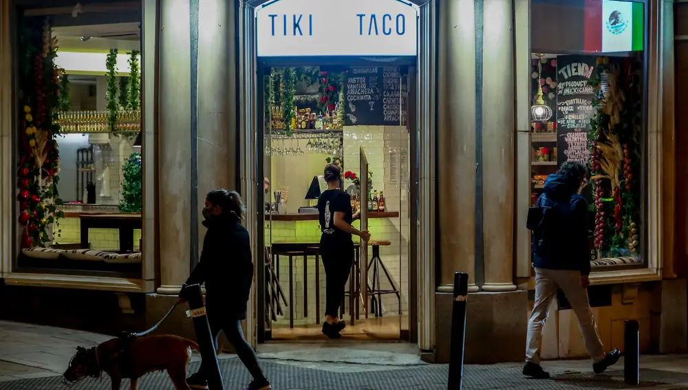 Una camarera recoge el cartel de un restaurante cerrado durante el primer día del toque de queda a las 10 de la noche, en Madrid