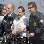 FILE - In this May 13, 2008 file photo, Colombian paramilitary Hernan Giraldo Serna, second right, is escorted by U.S. DEA Agents at his arrival in Opa-locka, Fla. Giraldo Serna has been deported from the US and returned to Colombian on Monday, January 25, 2021, after finishing a 16-year sentence in a U.S. prison for drug trafficking earlier this month. (AP Photo/Alan Diaz, File)
