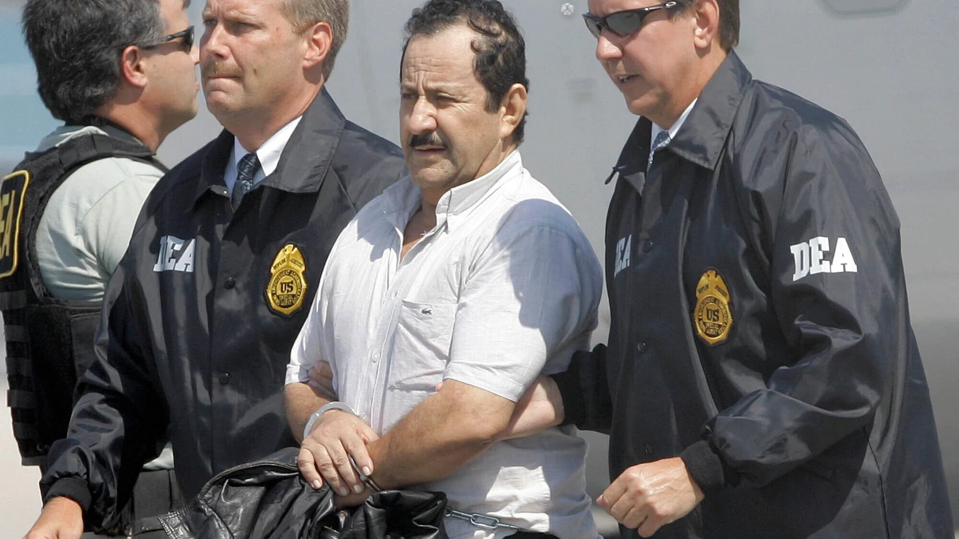 FILE - In this May 13, 2008 file photo, Colombian paramilitary Hernan Giraldo Serna, second right, is escorted by U.S. DEA Agents at his arrival in Opa-locka, Fla. Giraldo Serna has been deported from the US and returned to Colombian on Monday, January 25, 2021, after finishing a 16-year sentence in a U.S. prison for drug trafficking earlier this month. (AP Photo/Alan Diaz, File)