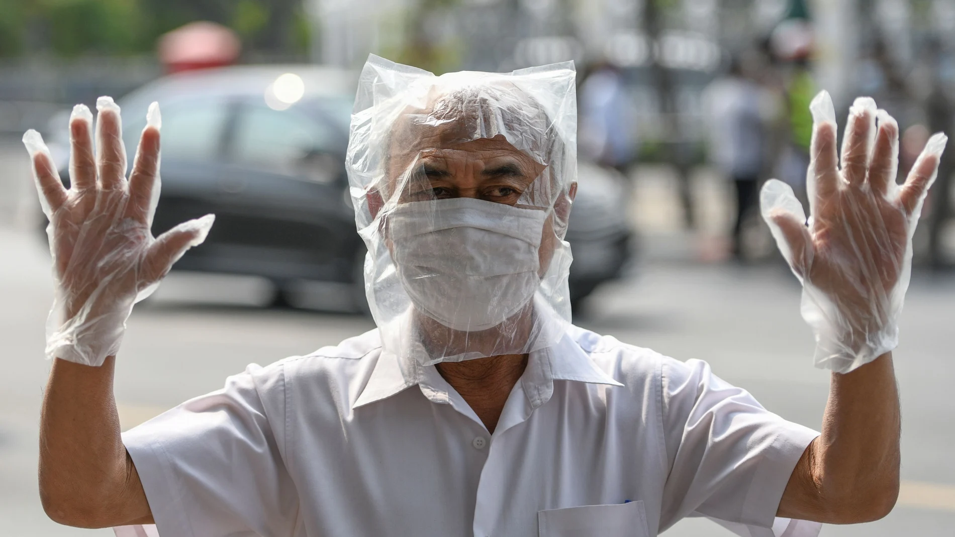 A man wearing a plastic bag as precaution against the coronavirus disease (COVID-19), takes part in protests demanding to reduce the Royal budget and distribute it to people, in front of the government house in Bangkok, Thailand January 26, 2021. REUTERS/Challinee Thirasupa