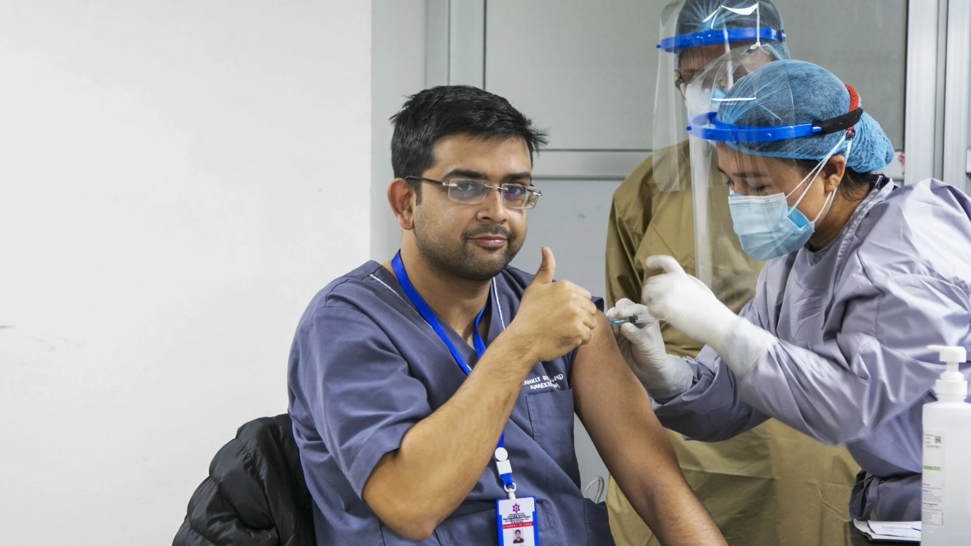 A Nepalese doctor shows thumbs up as he receives AstraZeneca/Oxford University vaccine, at Teaching Hospital in Kathmandu, Nepal, Wednesday, Jan. 27, 2021. Thousands of health workers lined up across Nepal to get the coronavirus vaccine Wednesday as the Himalayan nation began its campaign to get the population vaccinated within three months. Neighboring India gifted Nepal 1 million doses of the vaccine manufactured under license by the Serum Institute of India. (AP Photo/Niranjan Shrestha)