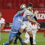 El delantero neerlandés del Sevilla Luuk De Jong (c-d) trata de ganar el balón ante la salida del portero Cristian Rivero (c-i), del Valencia