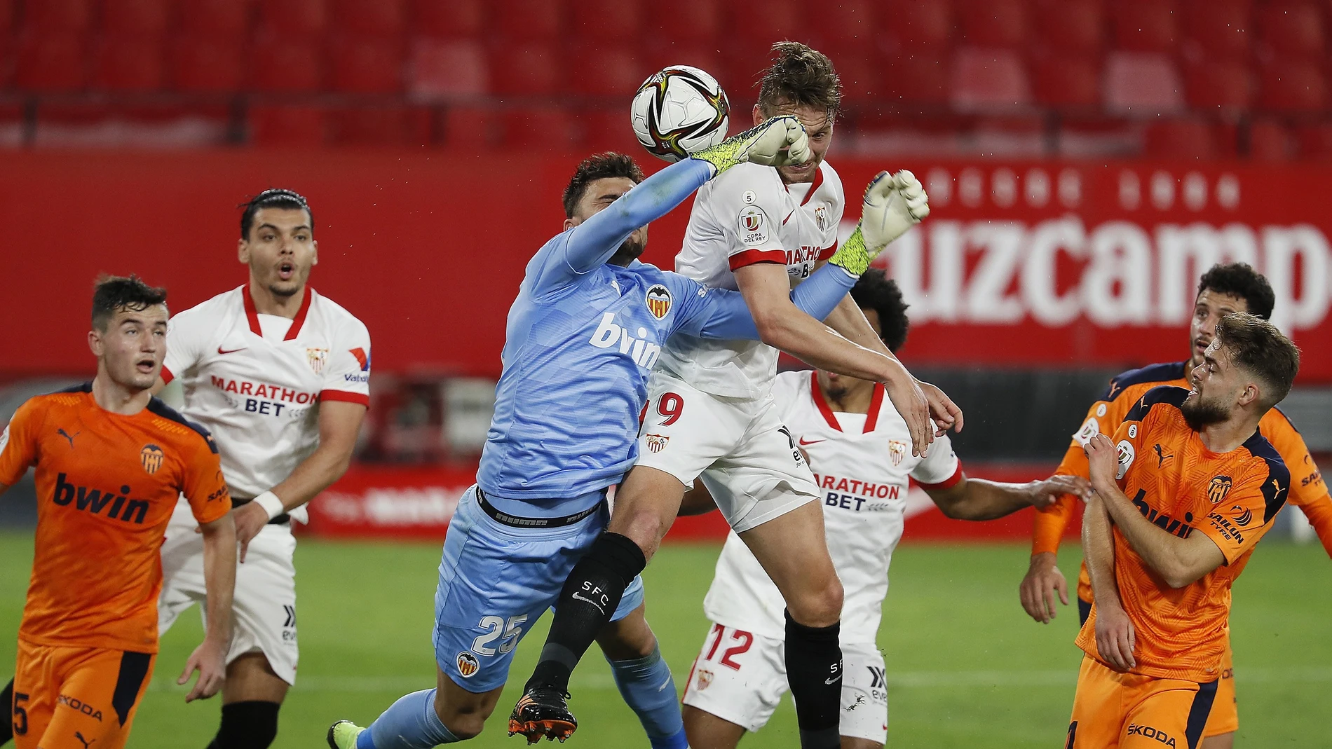 El delantero neerlandés del Sevilla Luuk De Jong (c-d) trata de ganar el balón ante la salida del portero Cristian Rivero (c-i), del Valencia