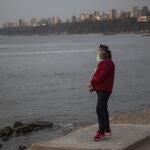 A woman wearing a mask and face shield to curb the spread of the new coronavirus stands on a platform overlooking the Pacific Ocean in Chorrillos, Lima, Peru, Tuesday, Jan. 26, 2021. (AP Photo/Rodrigo Abd)