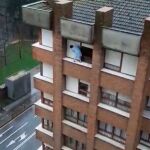 Imagen de una mujer subida al alféizar de una ventana de un séptimo piso en Gijón