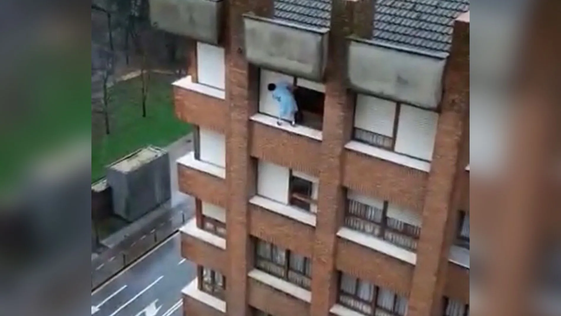 Imagen de una mujer subida al alféizar de una ventana de un séptimo piso en Gijón