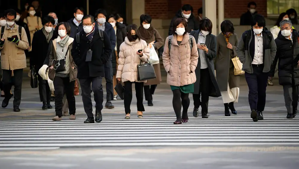 Unos transeúntes cruzan una calle en el distrito comercial de Otemachi en Tokio, Japón