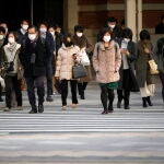 Unos transeúntes cruzan una calle en el distrito comercial de Otemachi en Tokio, Japón