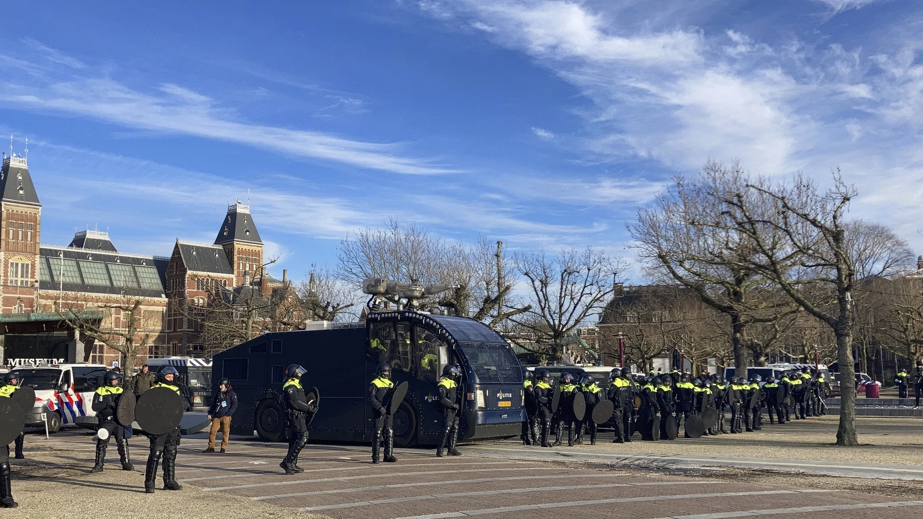 Policías antidisturbios holandeses se alinean frente al Rijksmuseum, atrás a la izquierda, mientras vigilan una manifestación contra el toque de queda y otras restricciones relacionadas con el COVID-19