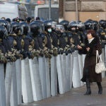 Una mujer pasa frente a la Policía antidisturbios en San Petersburgo, el domingo 31