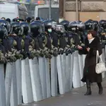 Una mujer pasa frente a la Policía antidisturbios en San Petersburgo, el domingo 31