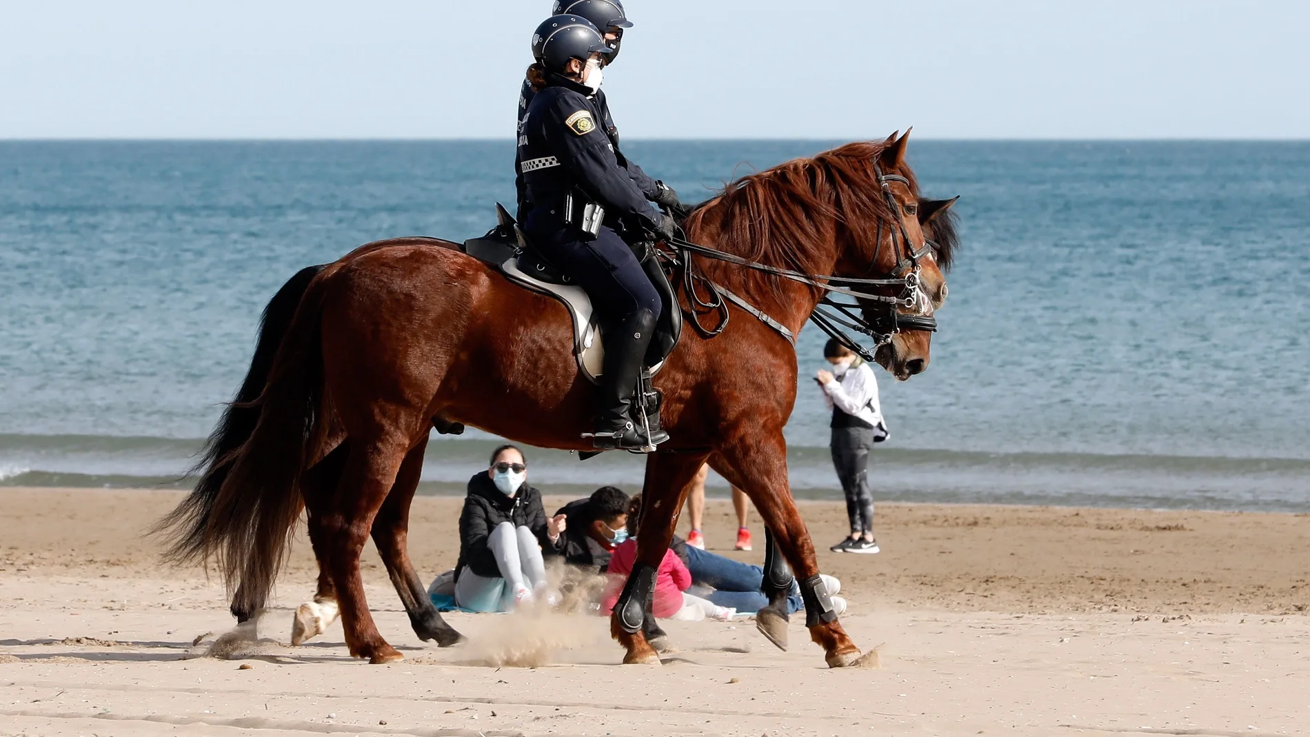 Una patrulla a caballo de la Policía Local de Valencia, vigila la playa de la Malvarrosa.