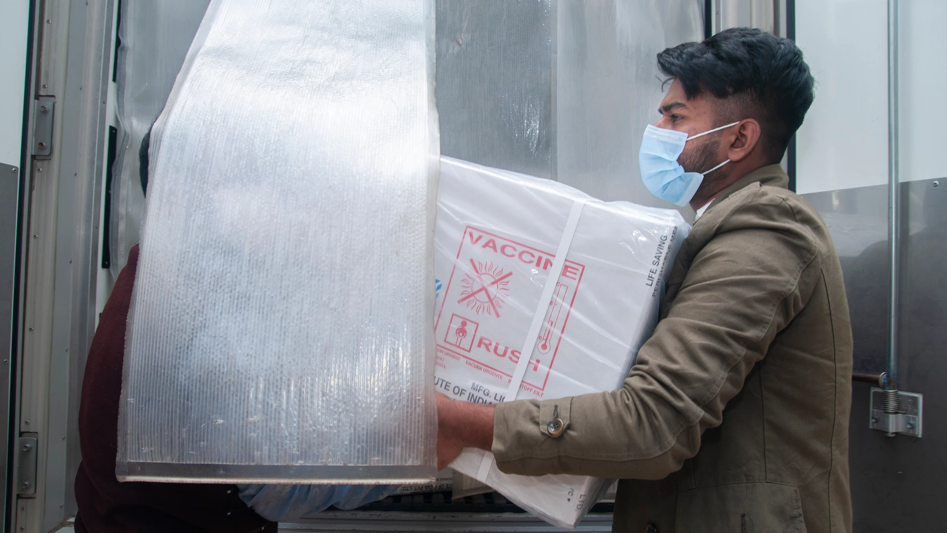 Un trabajador descarga una caja con viales de la vacuna de AstraZeneca en Bangladesh