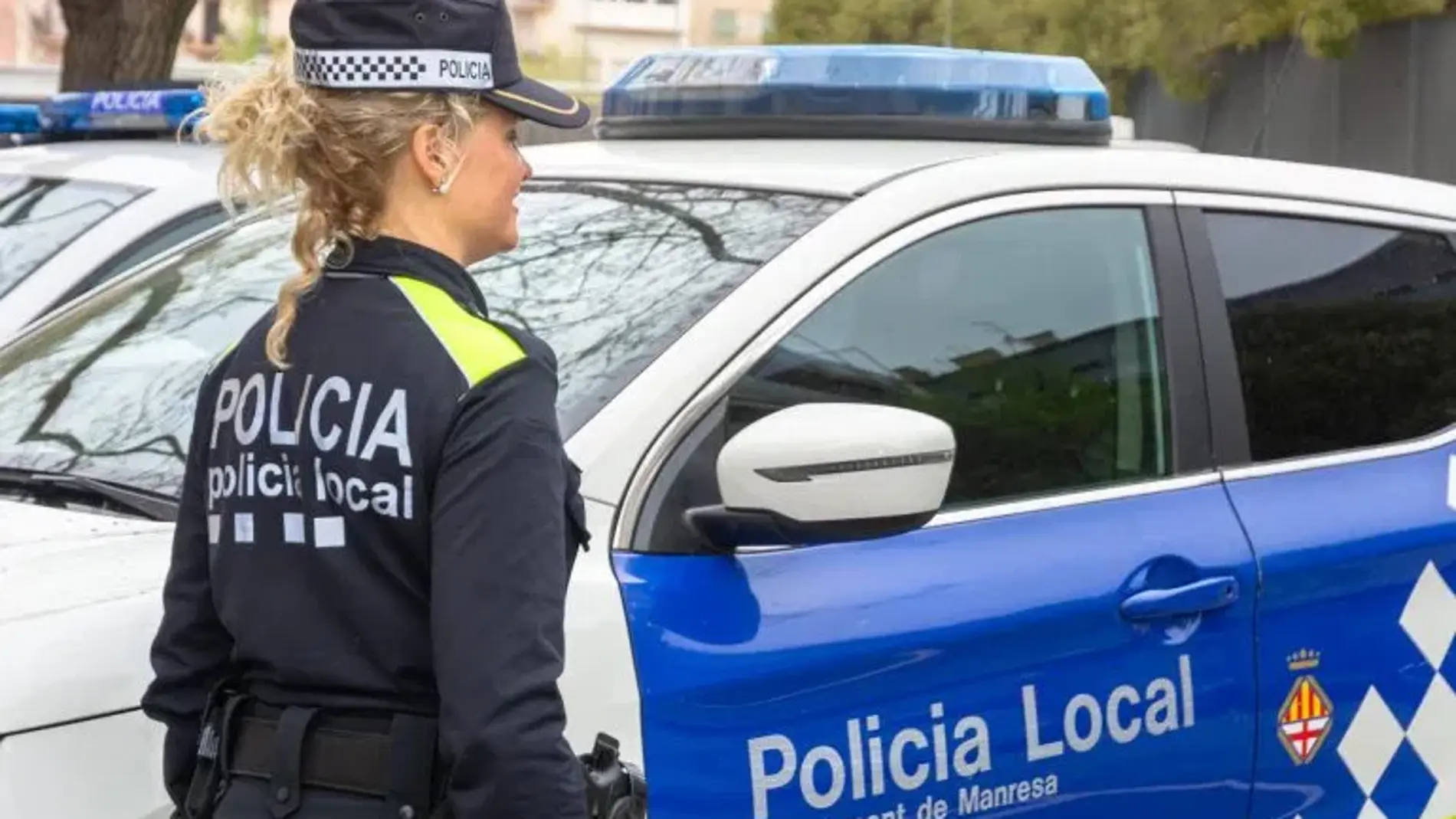 En la imagen, una agente y un coche patrulla de la Policía Local de Manresa