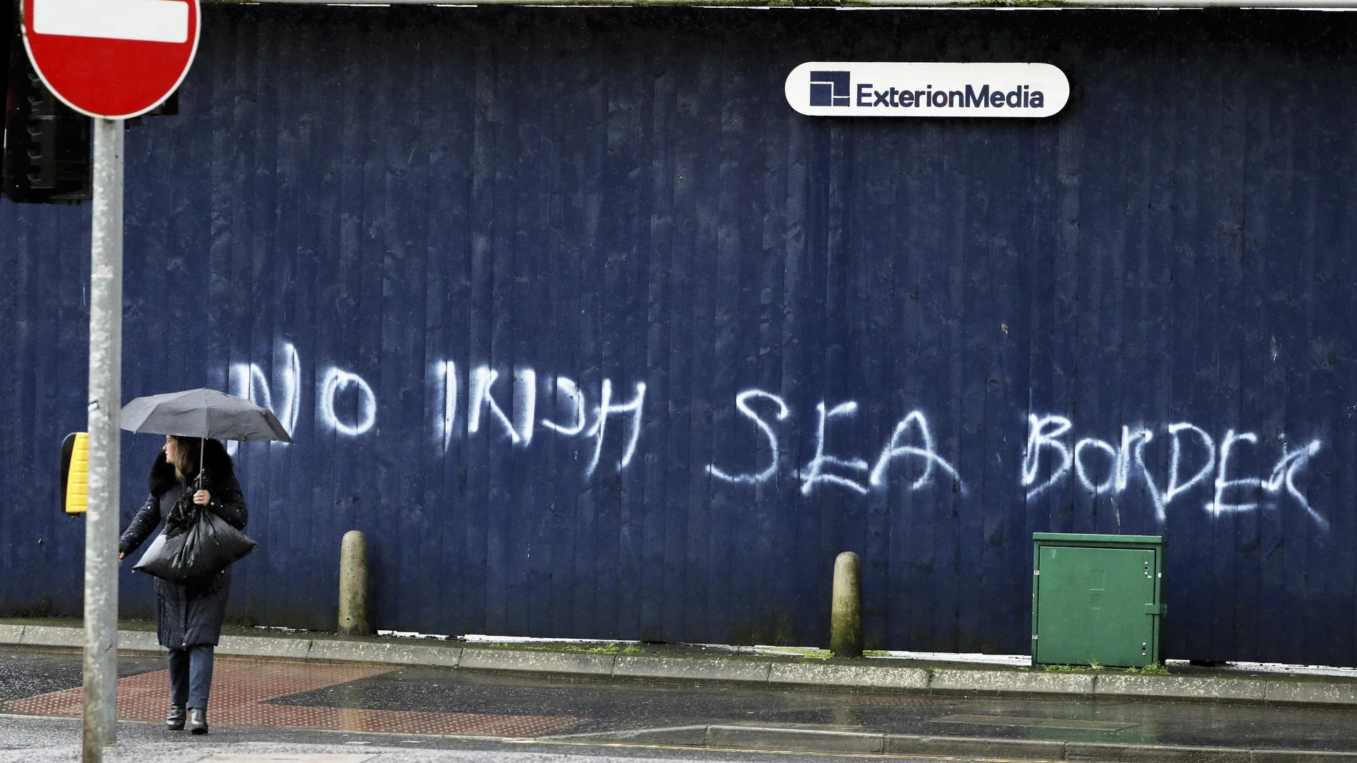 Una mujer pasa frente a un graffiti en el que se puede leer "No a la frontera marítima irlandesa" en el centro de Belfast, Irlanda del Norte