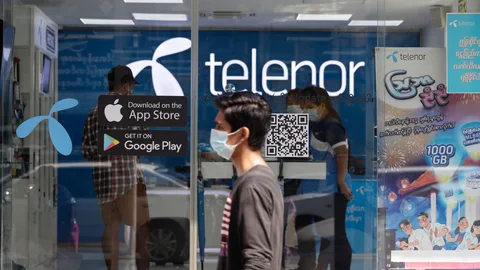 Un hombre pasa junto a un centro de Telenor en Yangon