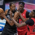 Kevin Durant, defendido por dos jugadores de los Raptors antes de tener que abandonar la cancha por el protocolo sanitario