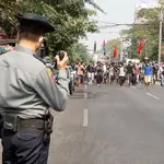 Un agente de policía habla por una radio policial mientras los manifestantes se manifiestan contra el golpe militar