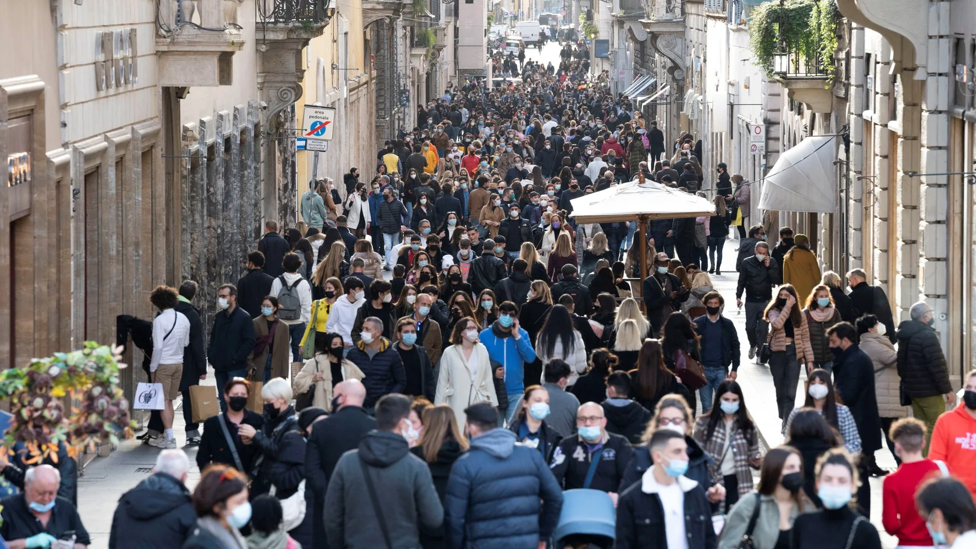 Centos de personas caminan por una abarrotada calle del centro de Roma (Italia)