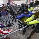 Insurrectos violentos leales a los partidarios de Trump tratan de romper una barrera policial en el Capitolio en Washington