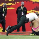 Un miembro de seguridad placa al espontáneo que saltó al campo durante la Super Bowl.