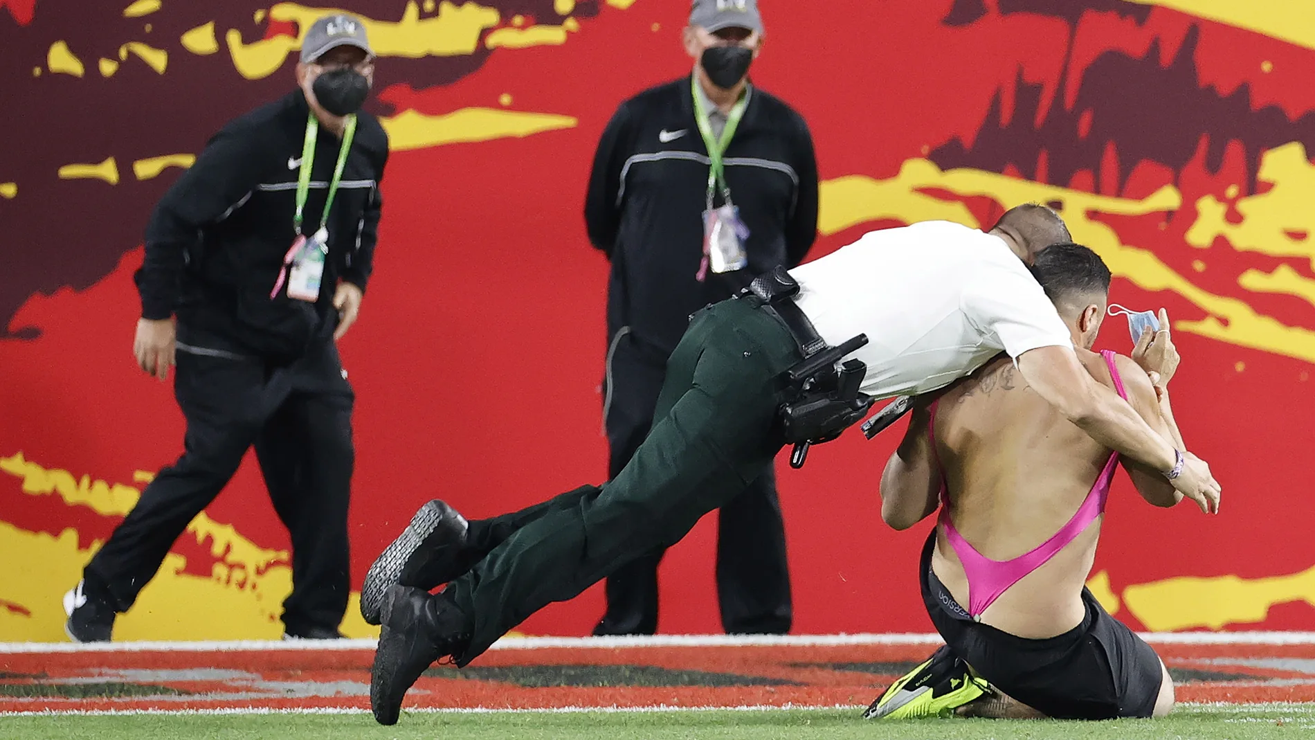 Un miembro de seguridad placa al espontáneo que saltó al campo durante la Super Bowl.