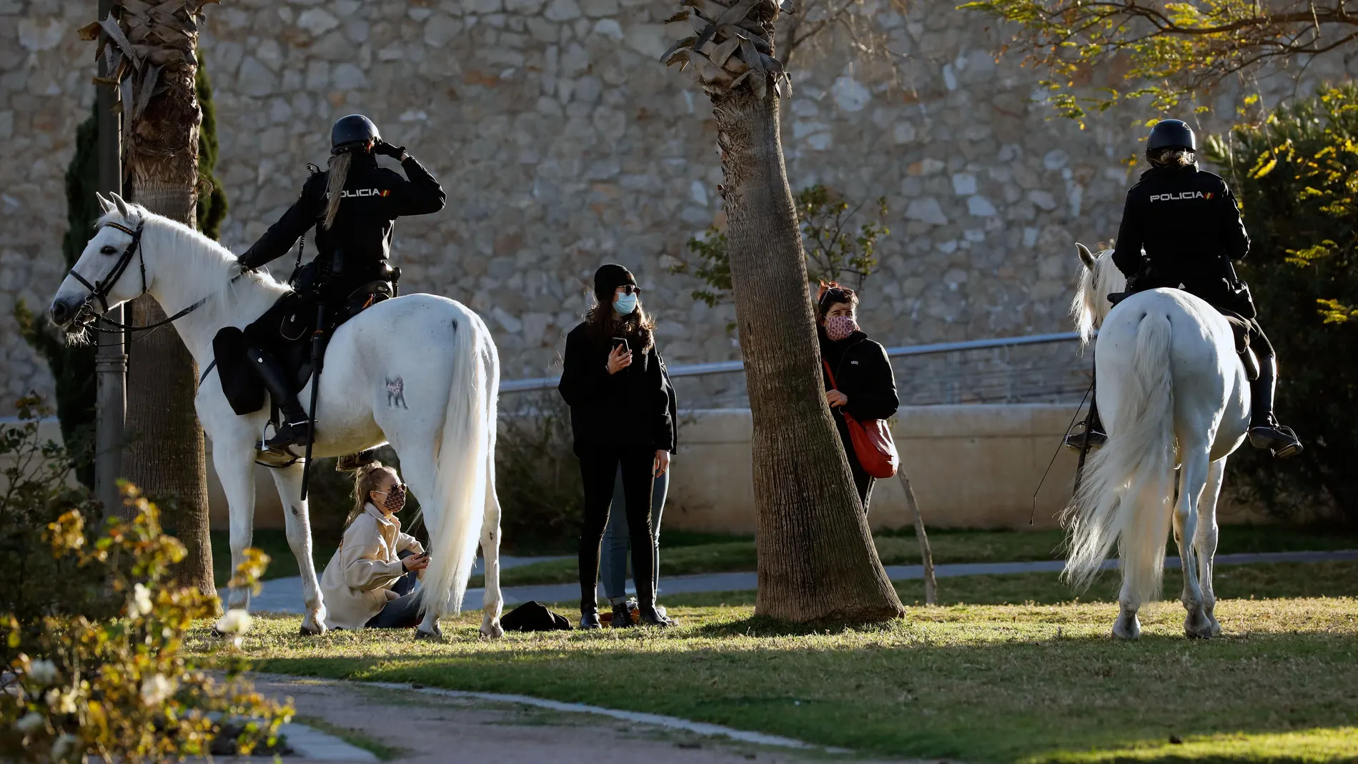 Una patrulla de Policia Nacional a caballo, controla que se cumplan el uso de las mascarillas en el antiguo cauce del río Turia, en Valencia