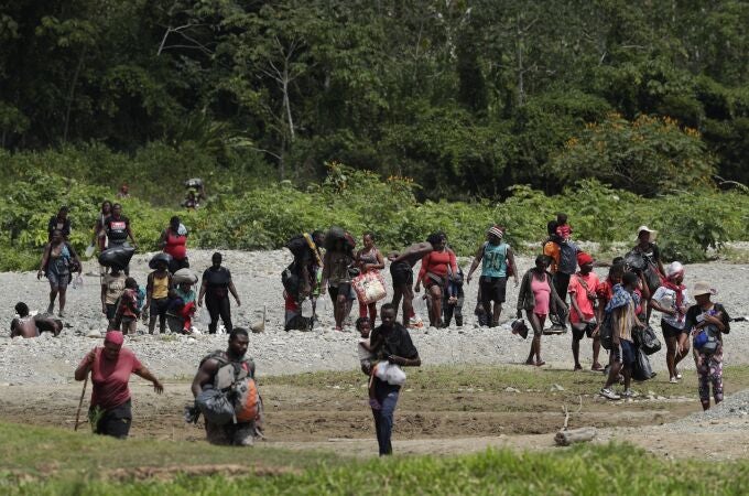 Migrants cross the Tuquesa river after a trip on foot through the jungle to Bajo Chiquito, Darien province, Panama, Wednesday, Feb. 10, 2021. Bajo Chiquito is the first population center that migrants coming from the Colombian border see when they cross over after several days of slogging through the jungle into Panama. (AP Photo/Arnulfo Franco)