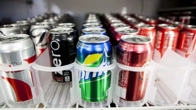 Latas de bebidas de refrescos en una nevera de un establecimiento