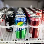 Latas de bebidas de refrescos en una nevera de un establecimiento