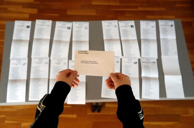 Una persona coge un sobre para las elecciones al Parlamento de Cataluña 2021
