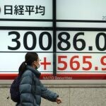 Una mujer camina frente a un distintivo de Nikkei en Japón