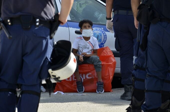 Un niño observa a varios policías en un campo de refugiados en la isla griega de Lesbos