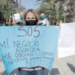 Una mujer perteneciente al sector hostelero de Alicante sostiene una pancarta en una manifestación