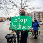 Un hombre con un cartel de "Stop desahucios" durante una manifestación por el derecho a la Vivienda en Atocha, a 21 de febrero de 2021