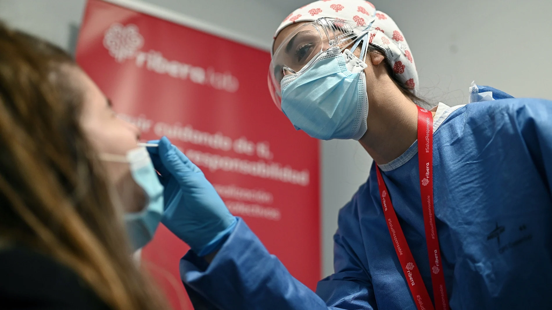 Una trabajadora sanitaria toma una muestra de saliva para un test de antígenos a una trabajadora en la estación de Atocha en Madrid