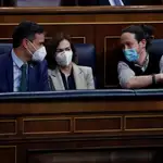 El presidente del Gobierno, Pedro Sánchez (i), conversa con sus vicepresidentes Carmen Calvo, y Pablo Iglesias durante un Pleno del Congreso